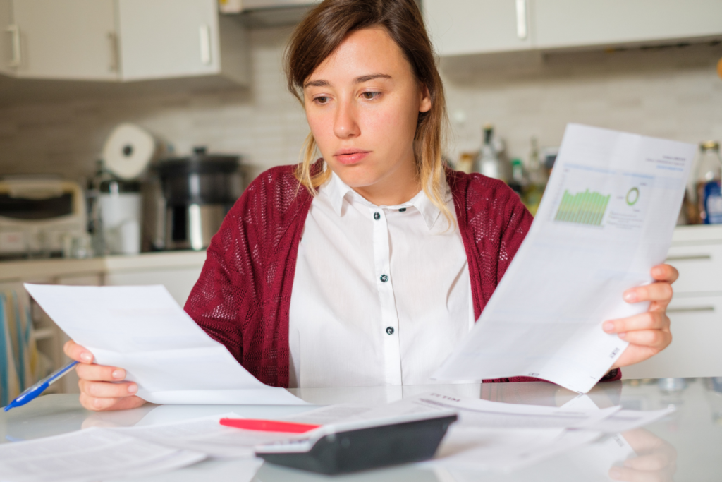 woman looking at her bills in her kitchen with worry